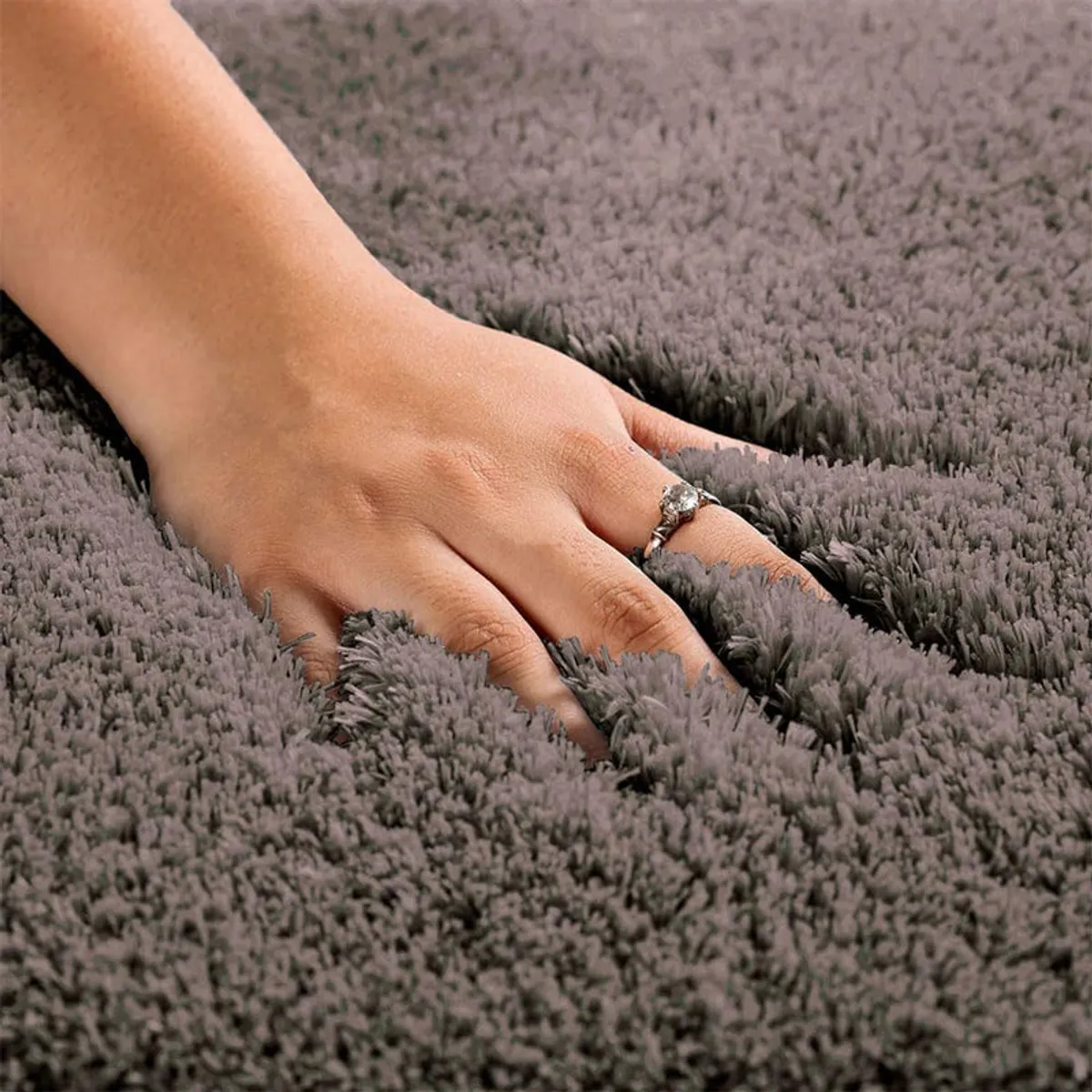 Hand pressing into the soft pile of a grey runner rug