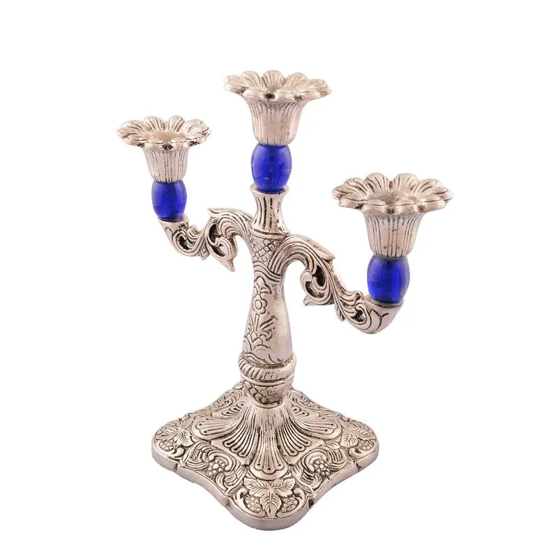 Angled view of the ornate silver-toned candle holder with blue accents