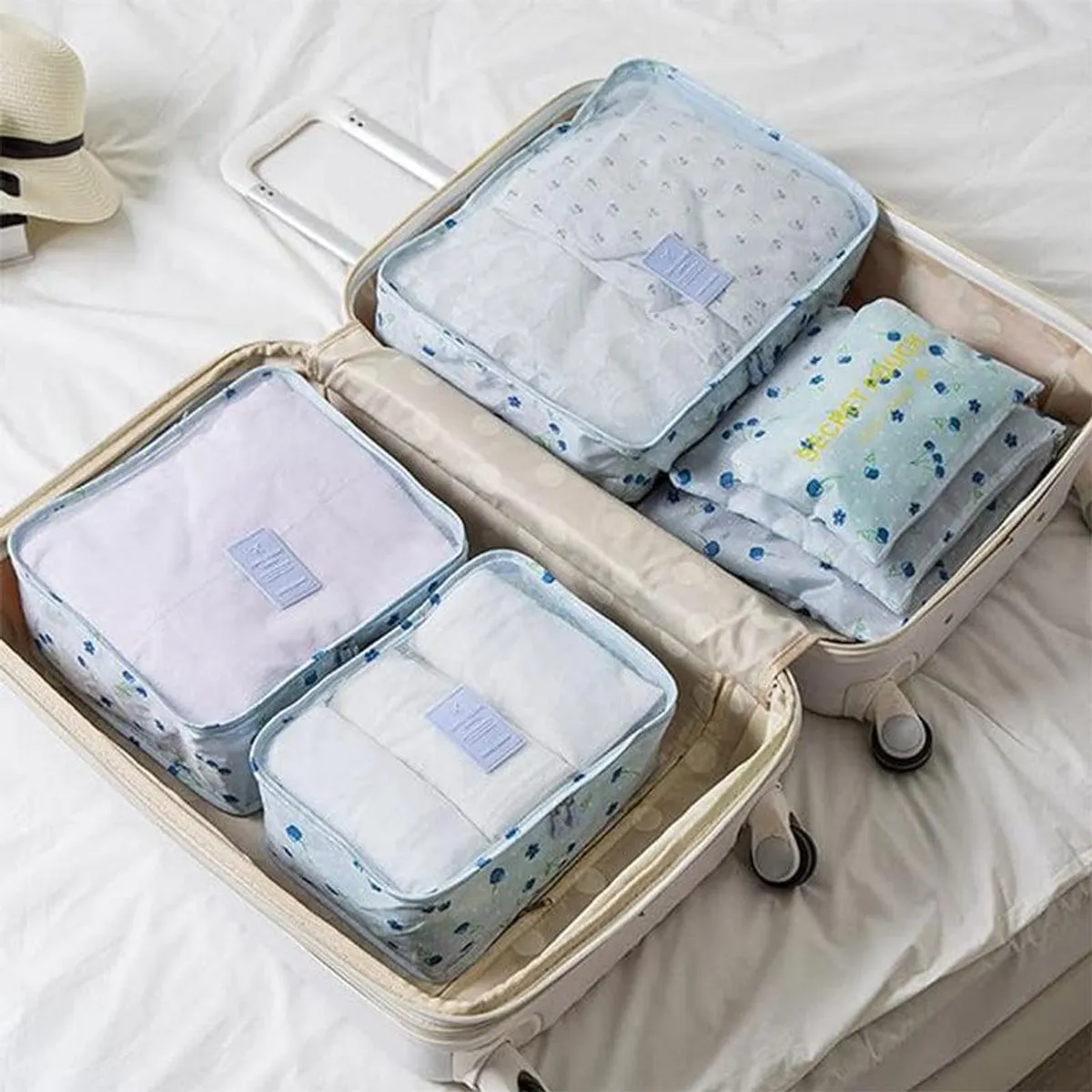 Blue floral organisers arranged inside two open suitcases on a bed.