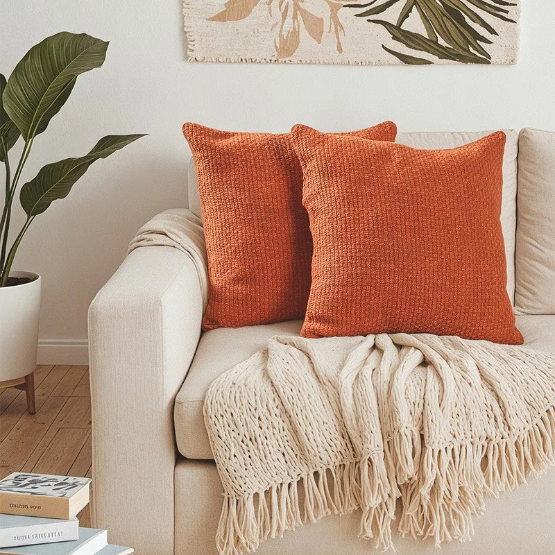 Two orange textured cushion covers styled on a cream sofa