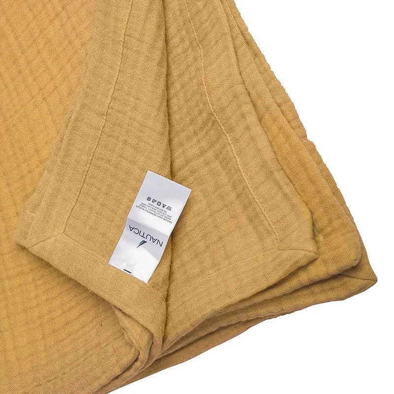 Close-up of folded yellow bedsheet showing its edge and care label