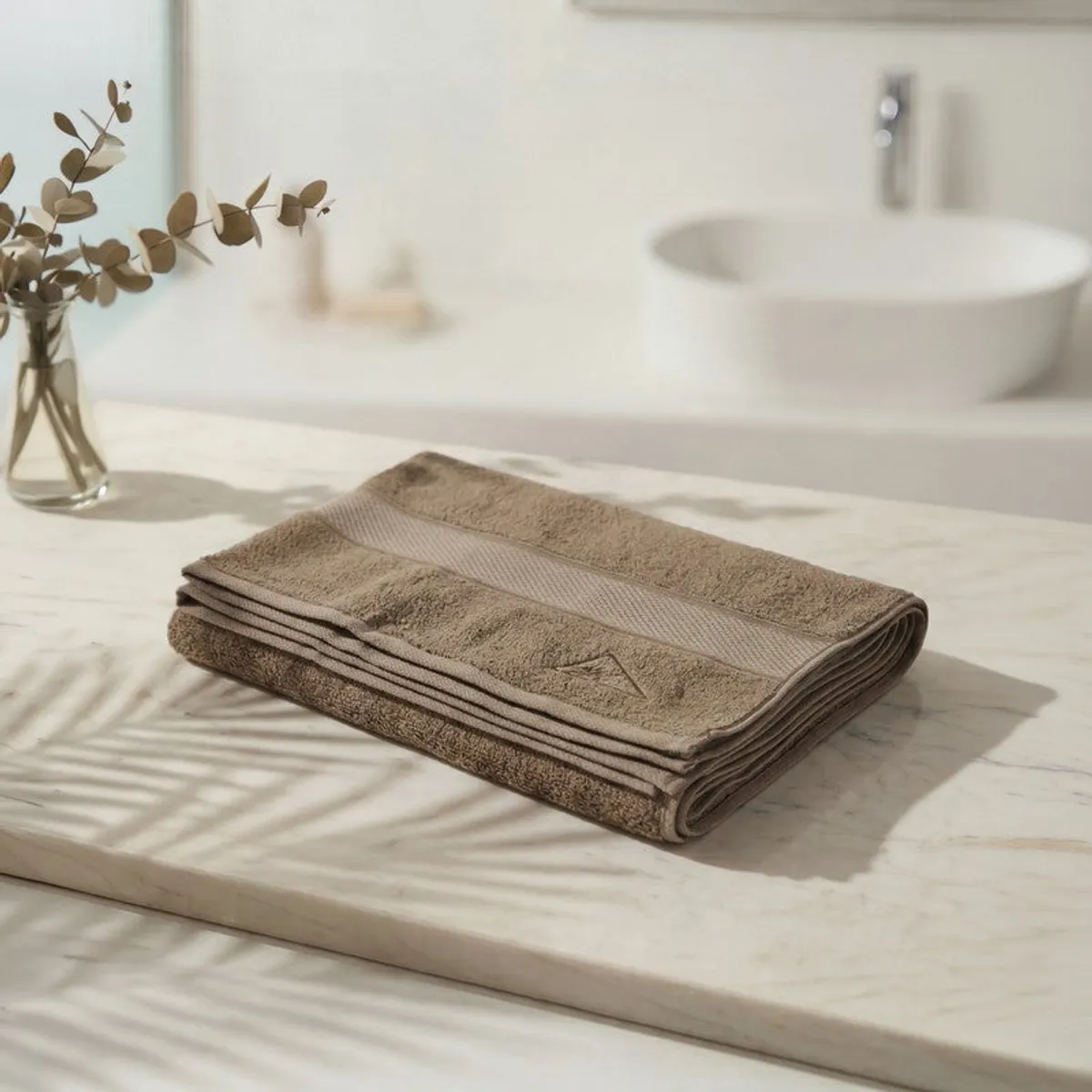 Folded brown bath towel displayed on a light bathroom counter.