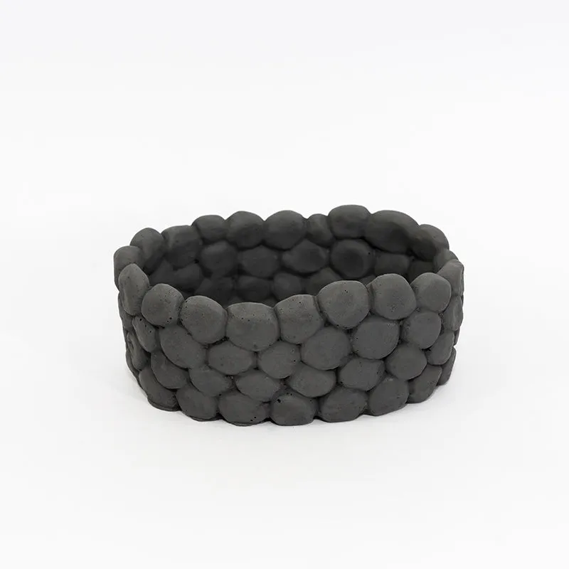 Grey oval accent bowl with rounded pebble-like surface on a white background