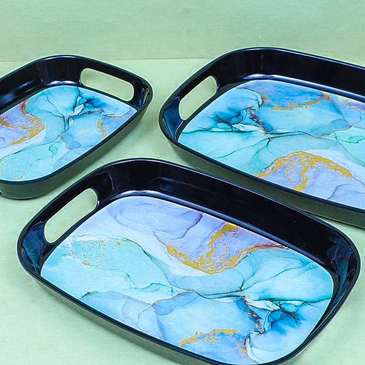 Close view of three black trays with blue marbled interiors and handles