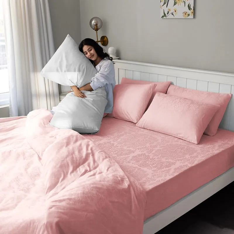 Pink floral duvet cover styled in a bright bedroom with a person sitting on the bed.