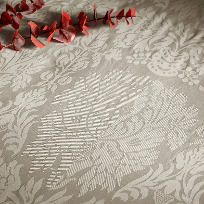 Close-up of the beige bedsheet's intricate floral jacquard pattern