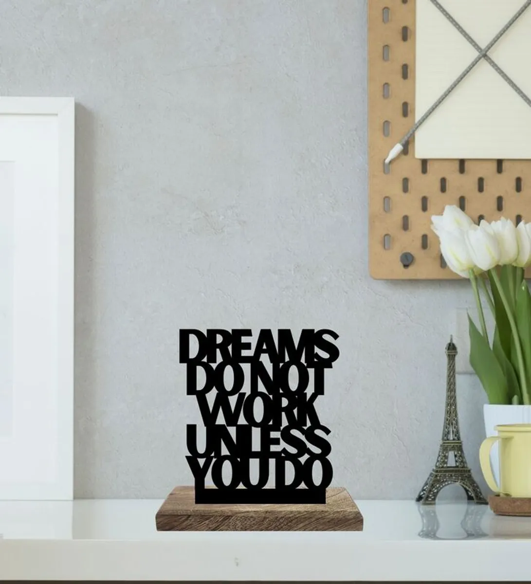 Black typography showpiece on a wooden base styled on a white shelf.