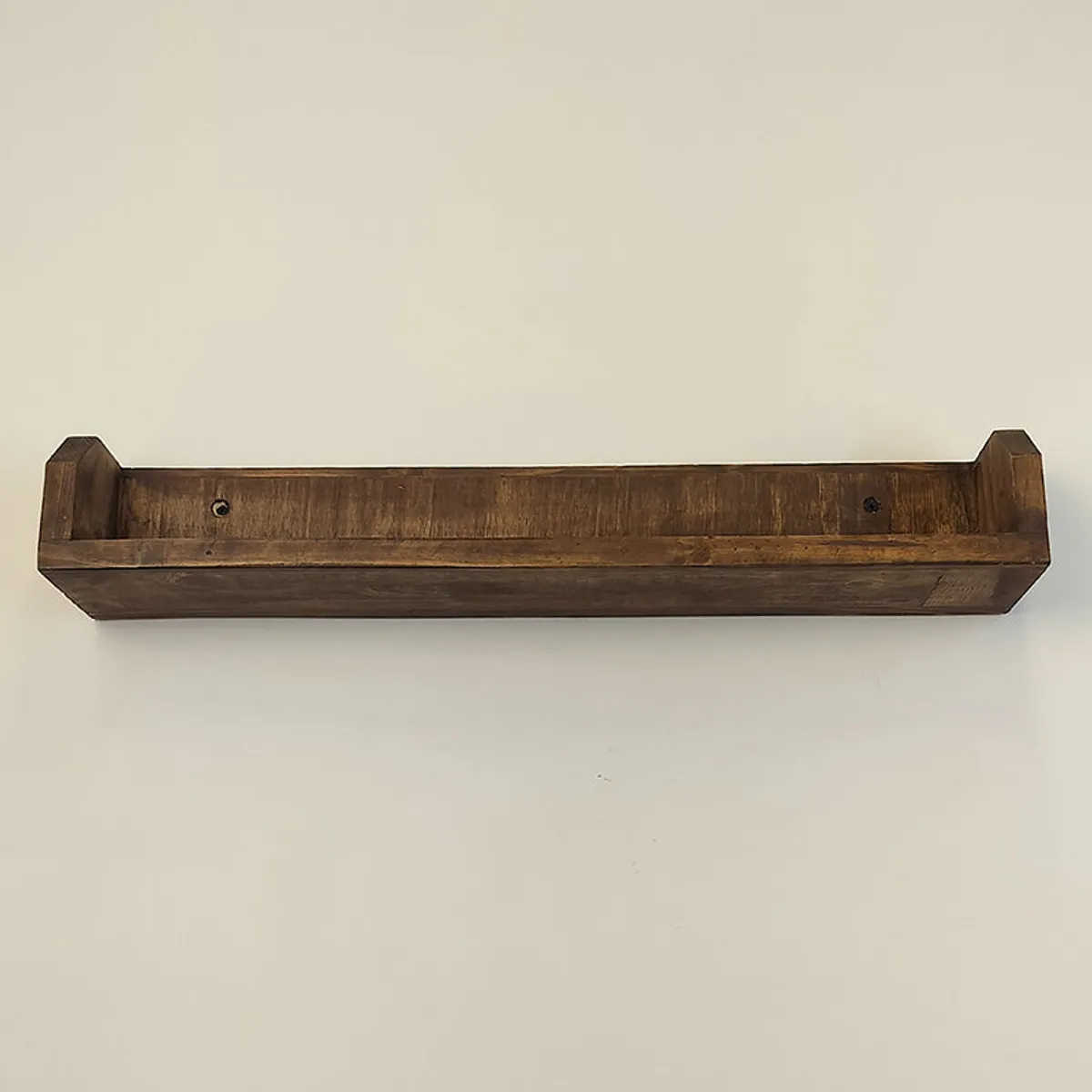 Front underside view of the brown wooden wall shelf showing its raised side edges and wall-mount holes.