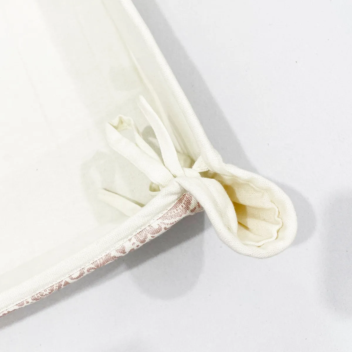 Close-up of tied corner detail on the cream cotton basket