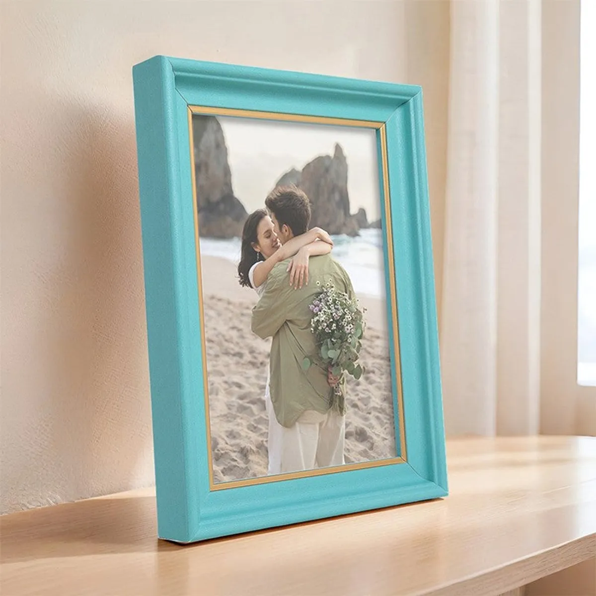 Blue and gold photo frame standing on a wooden surface beside a bright window