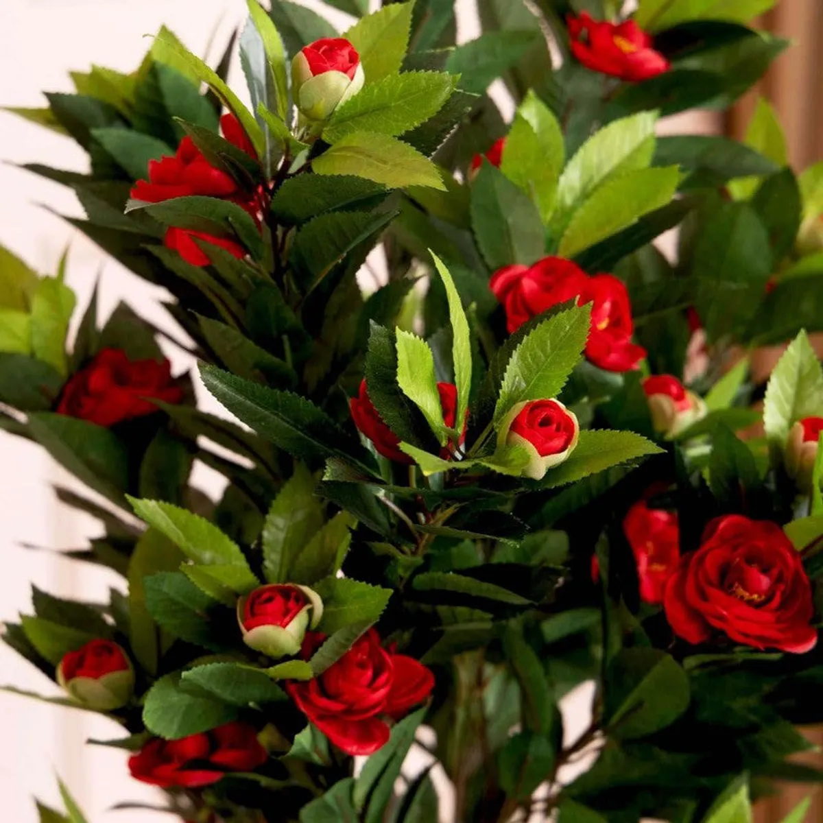 Close-up of red artificial flowers and green leaves with unopened buds