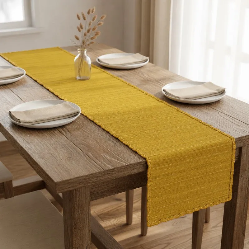 Yellow table runner placed lengthwise on a light wooden dining table.