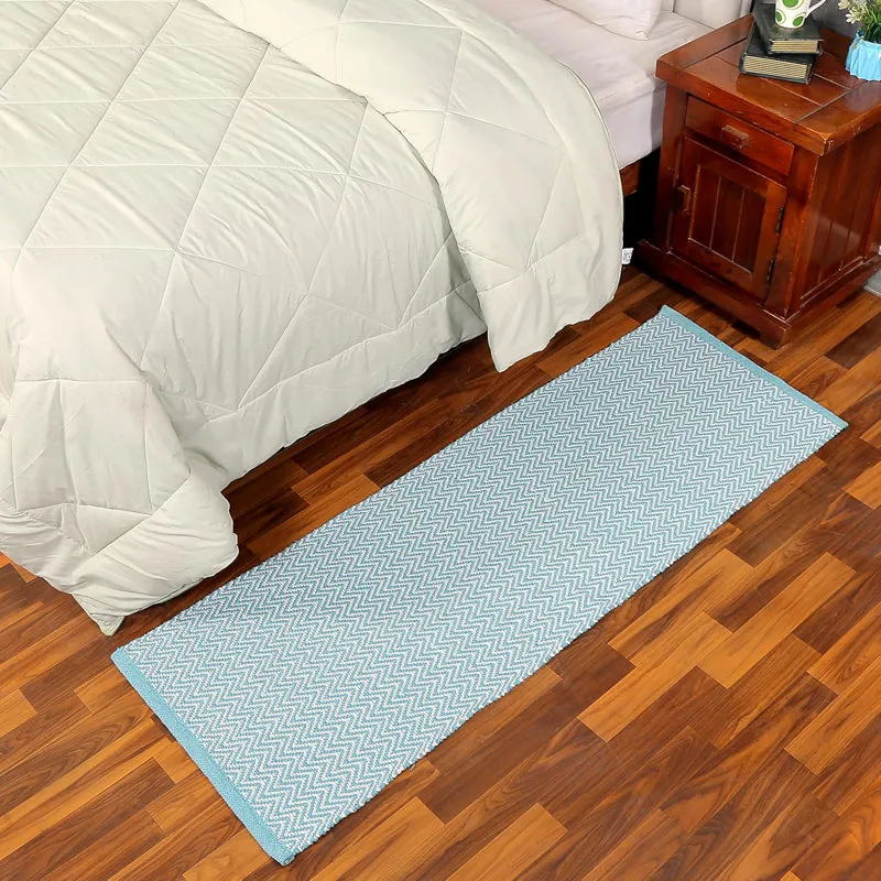 Sky blue runner rug placed beside a bed on wooden flooring