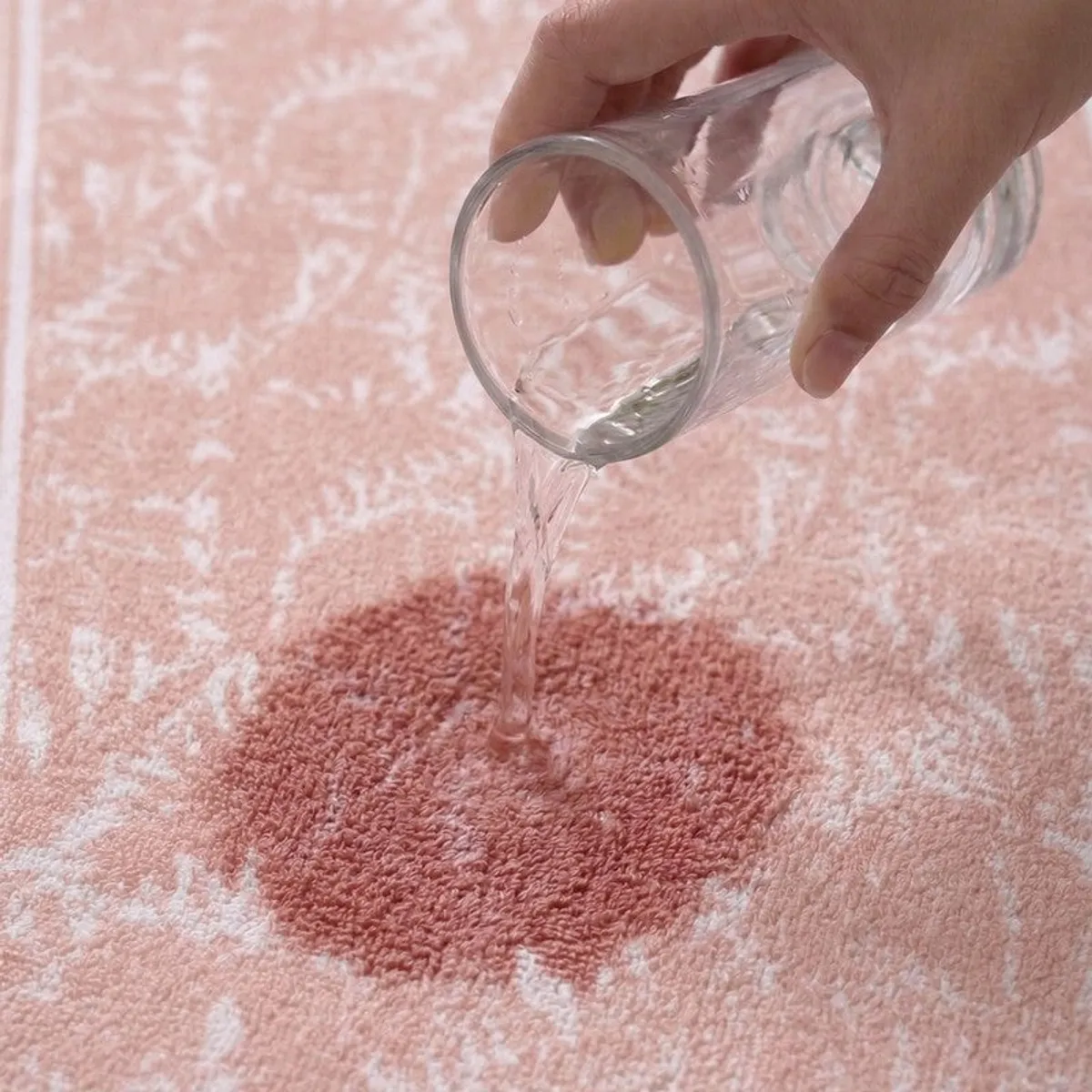 Water being poured onto the absorbent surface of a peach patterned bath towel