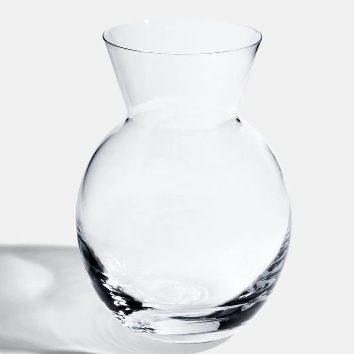Full view of a clear rounded glass vase with a flared neck