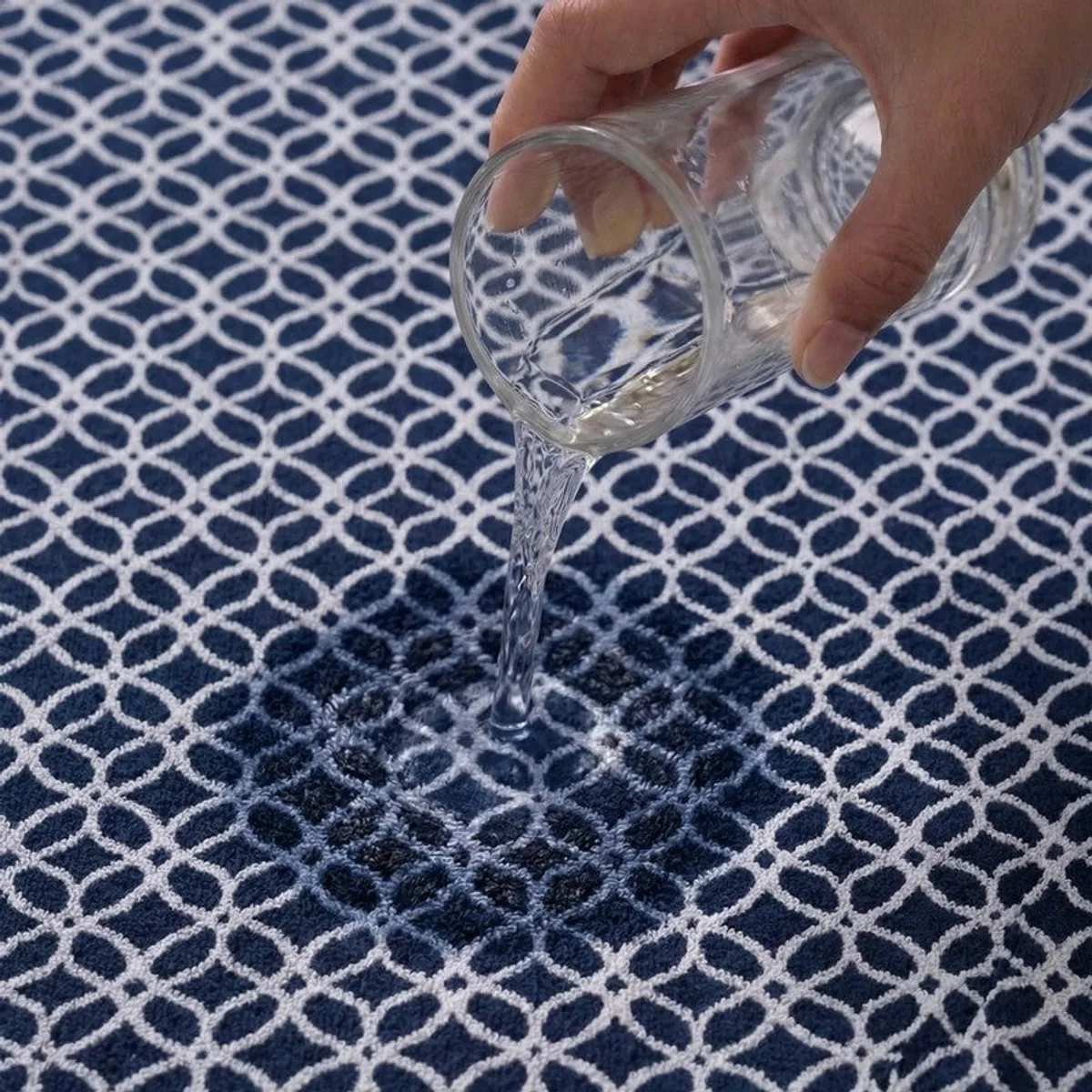 Water being poured onto the absorbent surface of a blue patterned towel