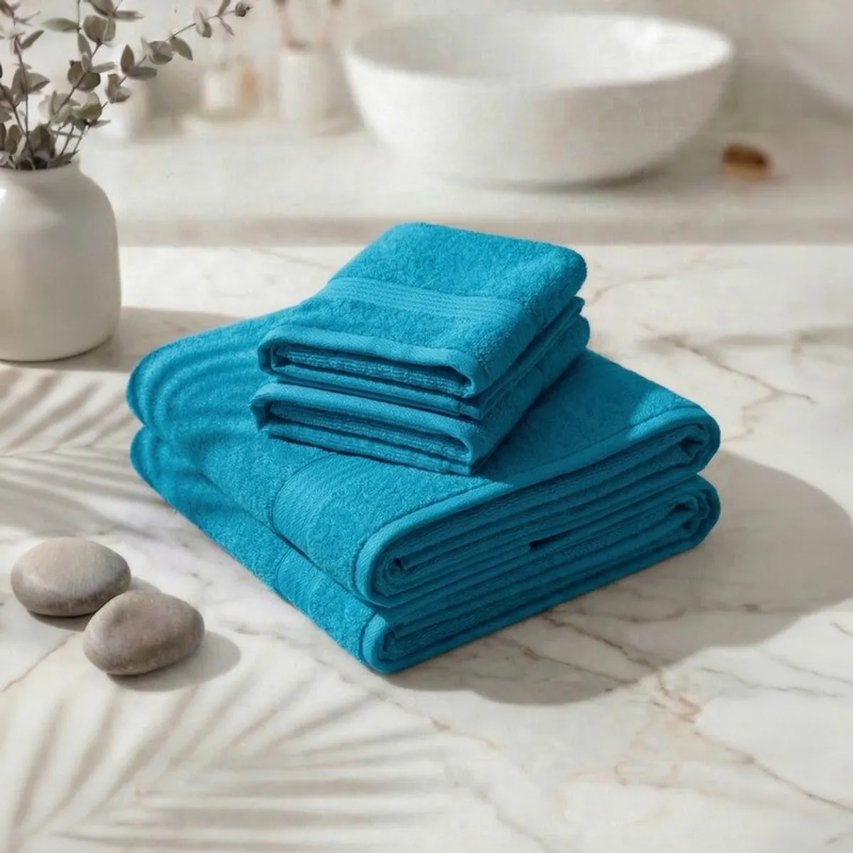 Folded stack of sky blue towels placed on a marble surface.