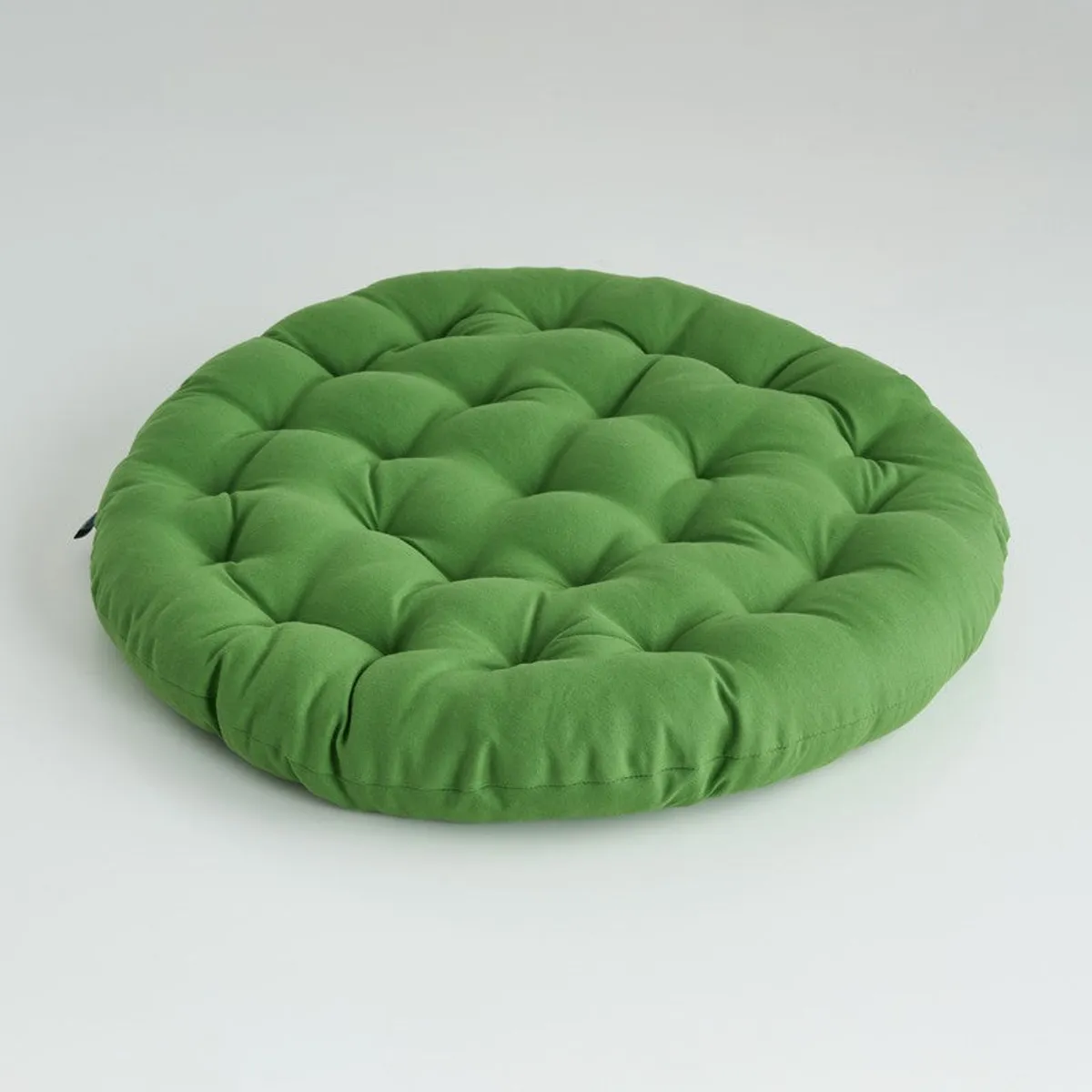 Single round light green floor cushion on a plain background
