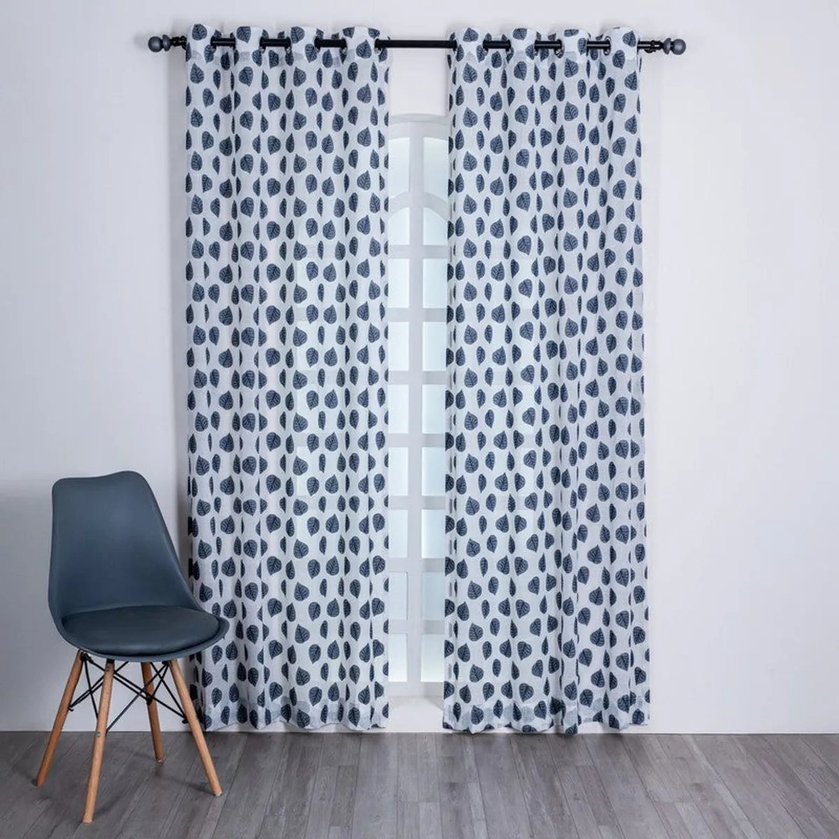 Grey sheer curtains with blue leaf motifs framing a tall window.