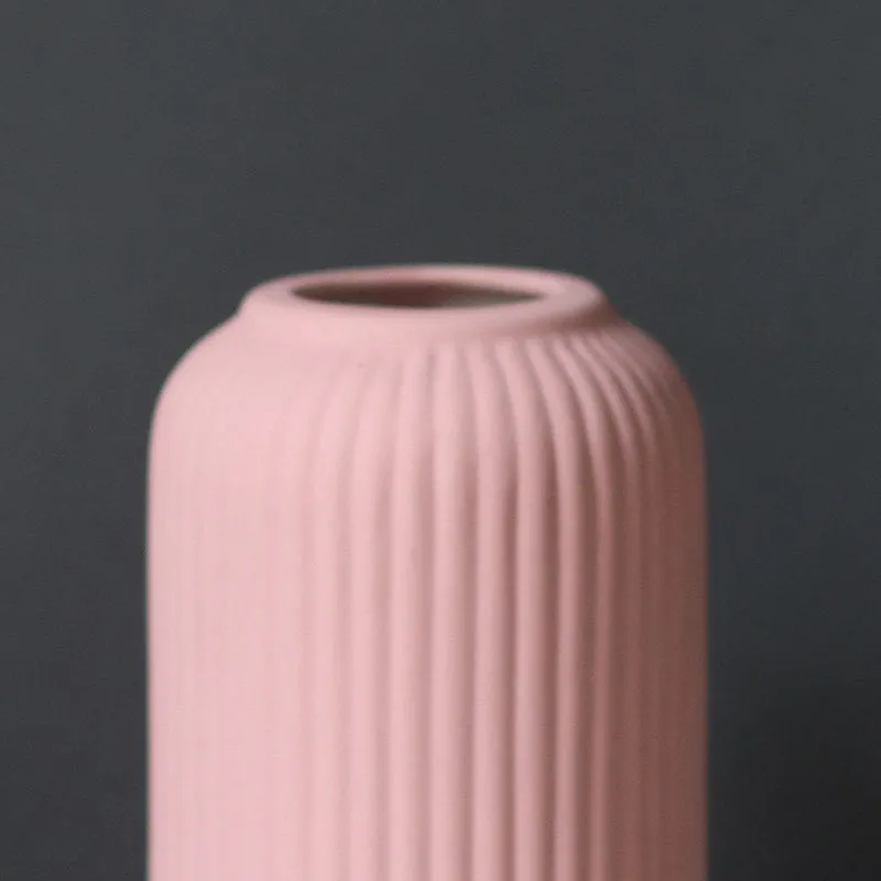 Close-up of the upper half of a pink ribbed vase against a dark background