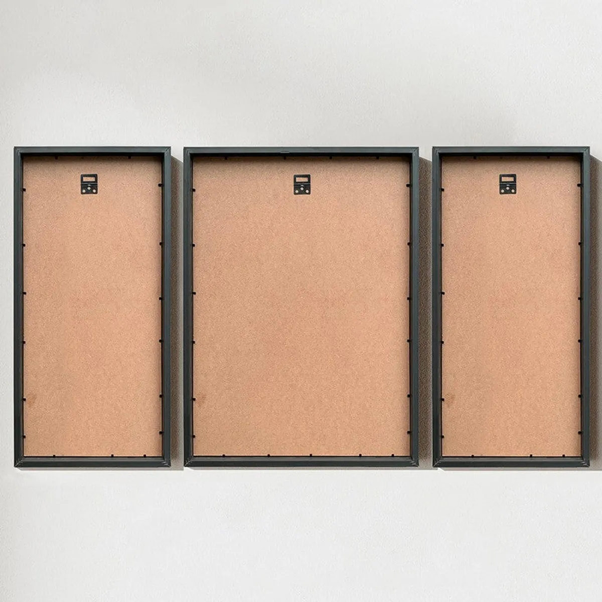 Rear view of three black frames with hanging hardware.