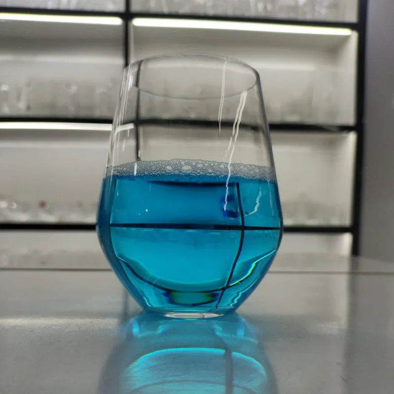 Single clear stemless glass filled with blue liquid