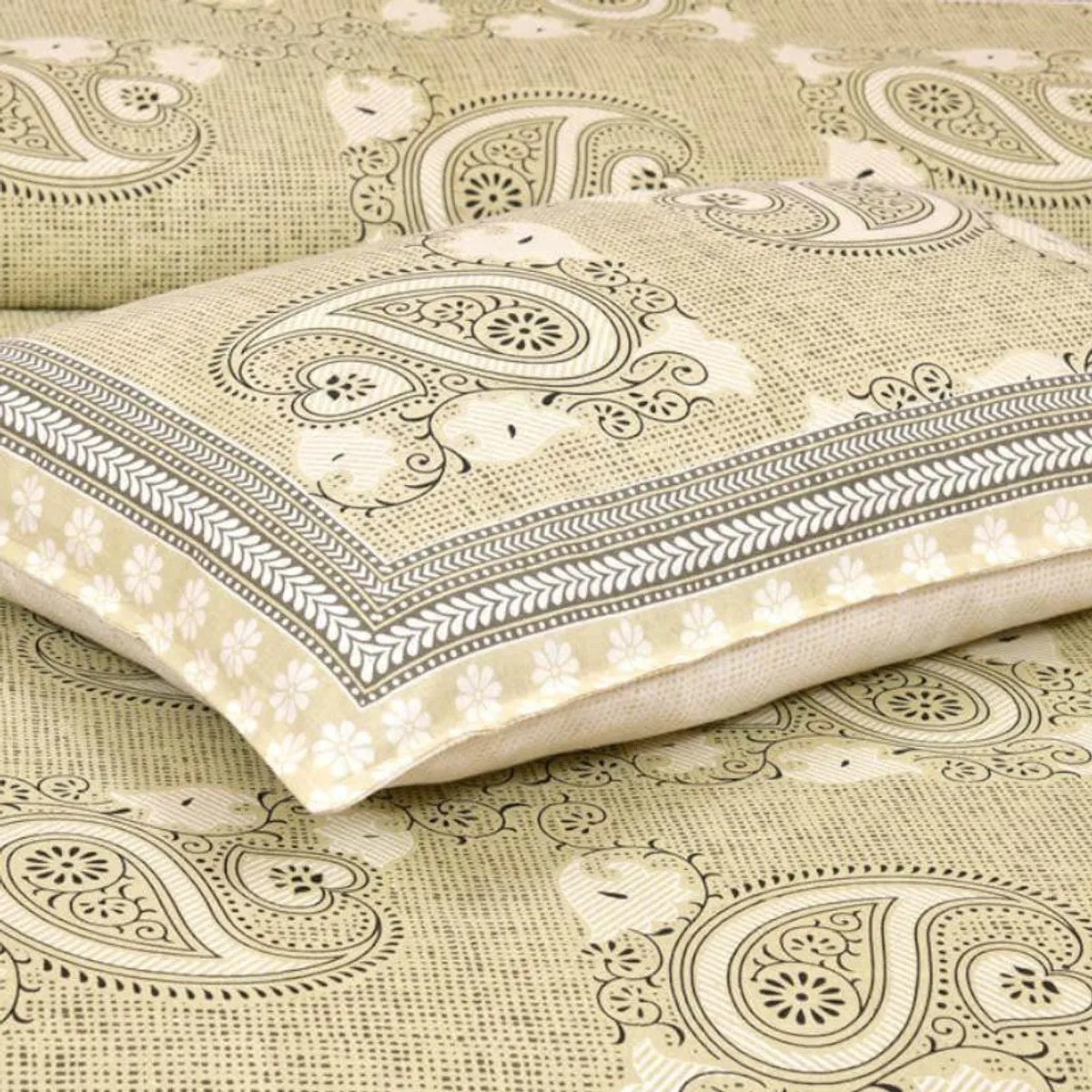 Folded yellow paisley pillow cover and bedsheet showing decorative border