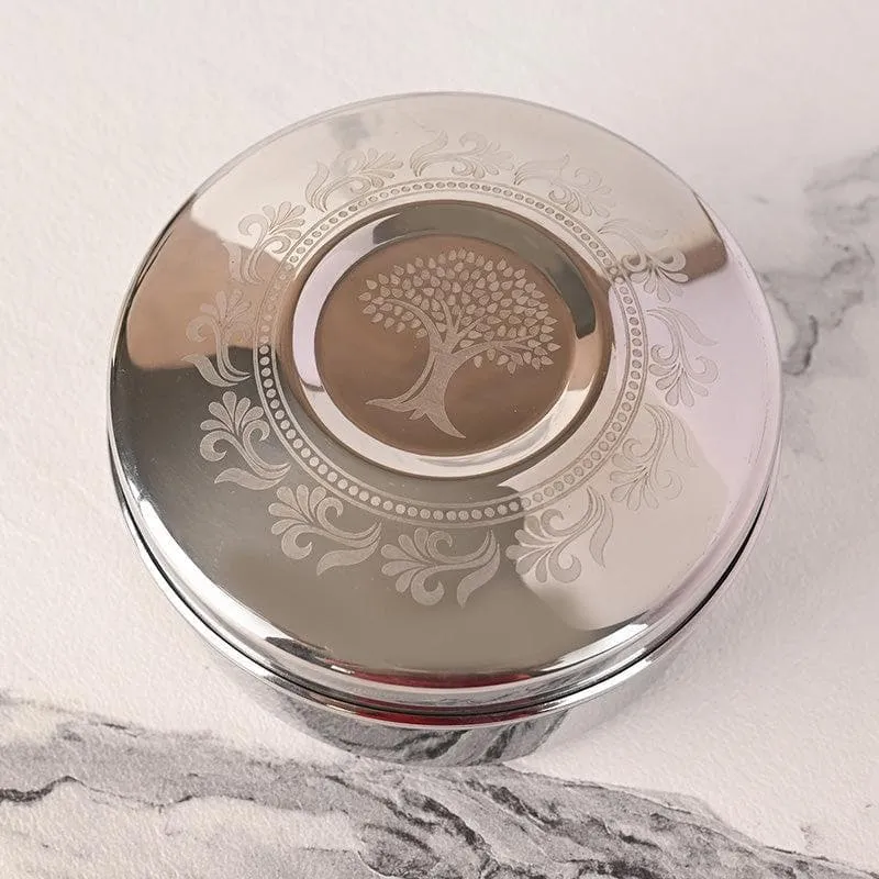 Close-up of a silver container lid with tree of life and ornamental design