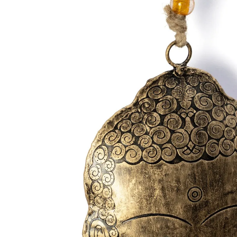 Close-up of ornate gold curls and Buddha-face detailing on the hanging bell