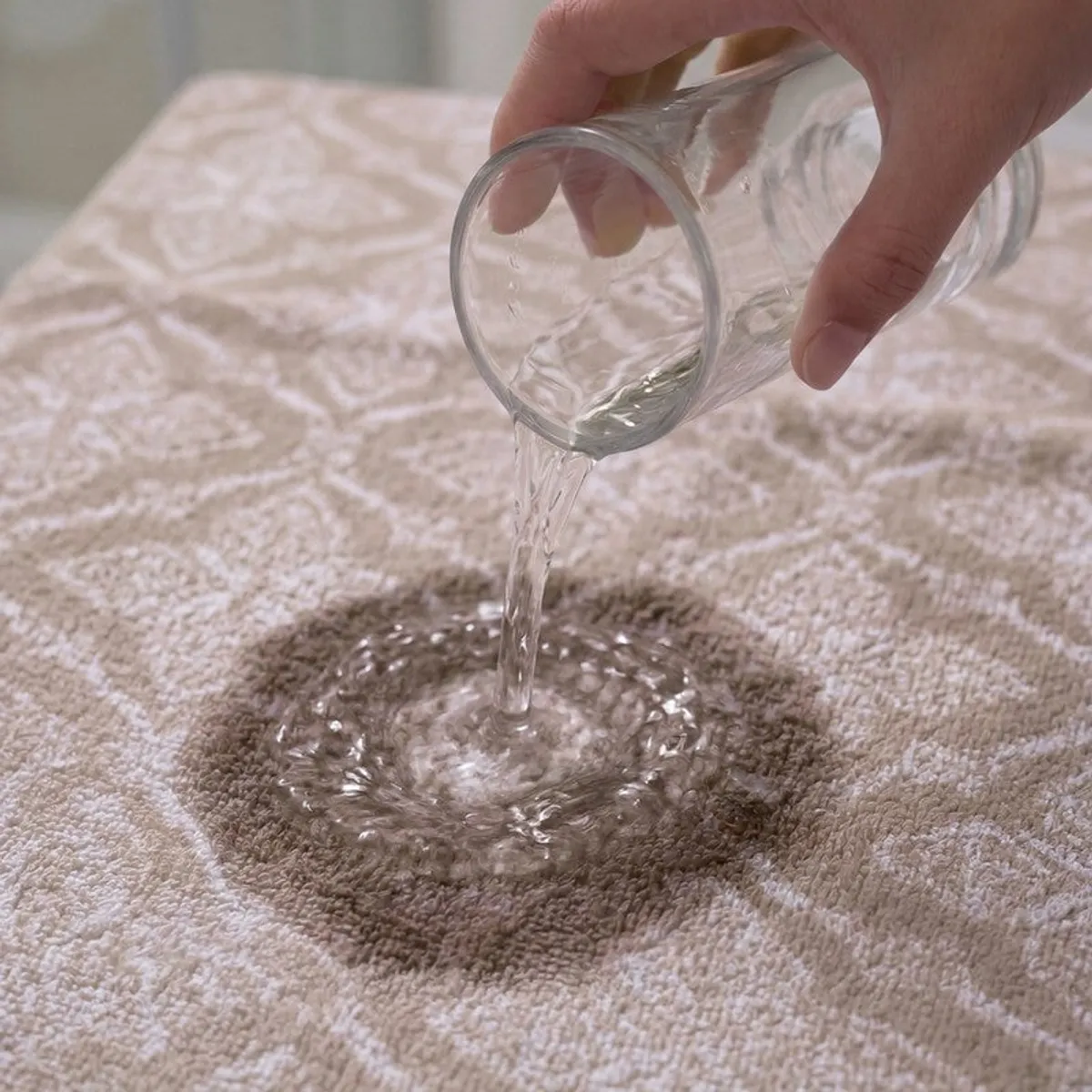 Water being poured onto the absorbent surface of a beige floral bath towel
