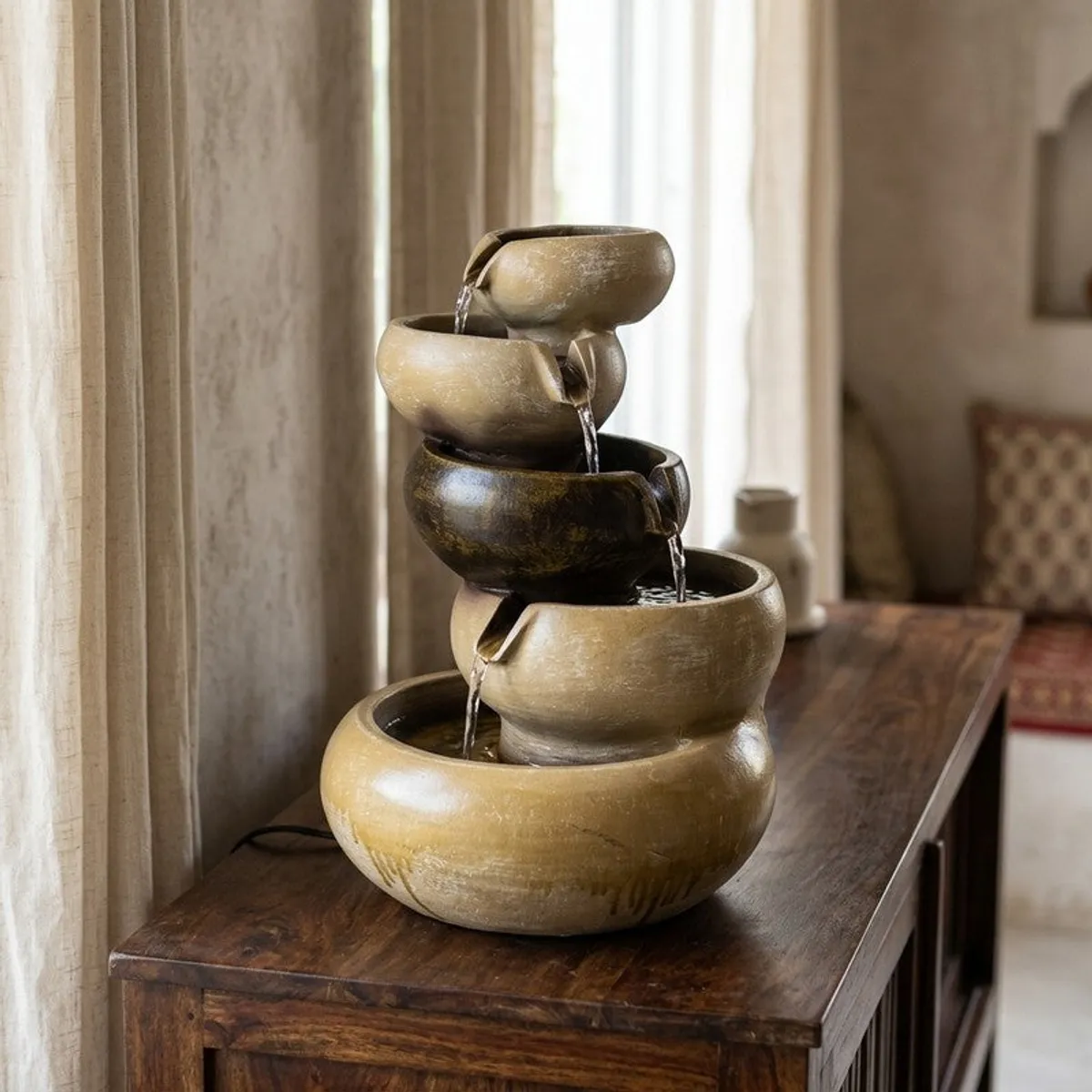 Beige and brown tiered water fountain displayed on a wooden console