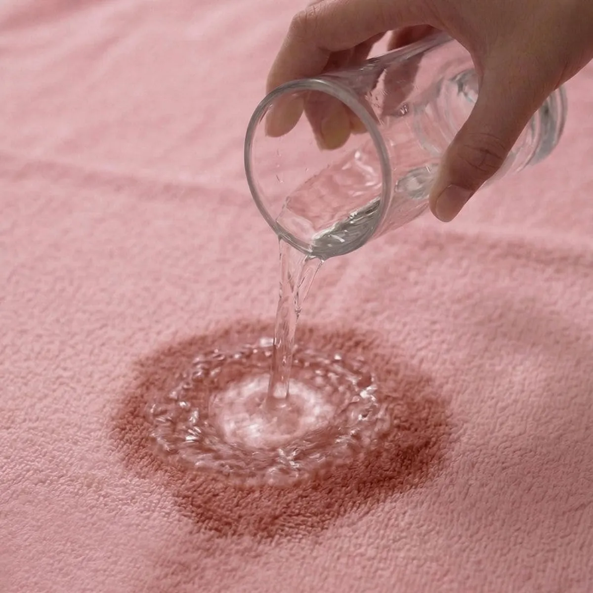 Water being poured onto the absorbent surface of a pink towel