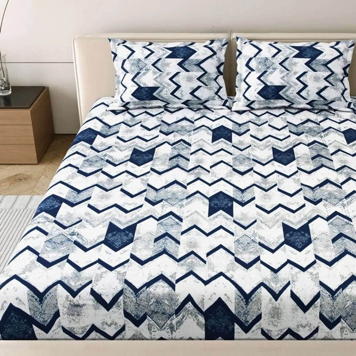 Geometric blue and white flat bedsheet styled across a bed
