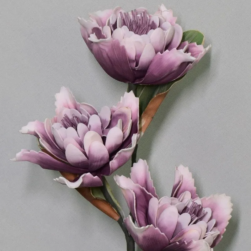 Close-up of three purple dahlia flowers with layered petals and green leaves