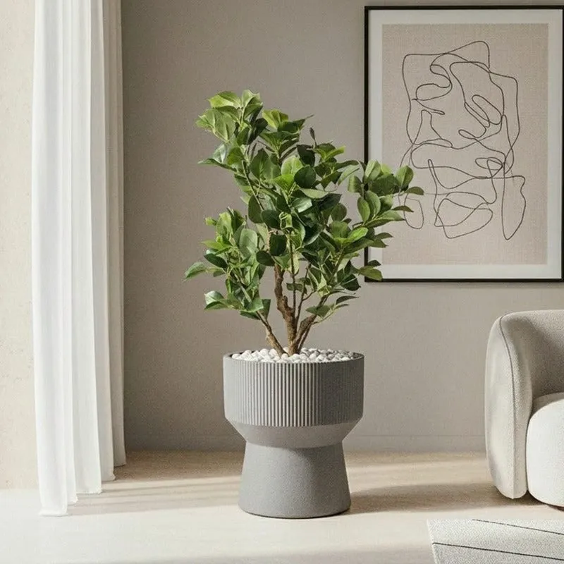 Grey hourglass planter with a leafy plant beside framed wall art