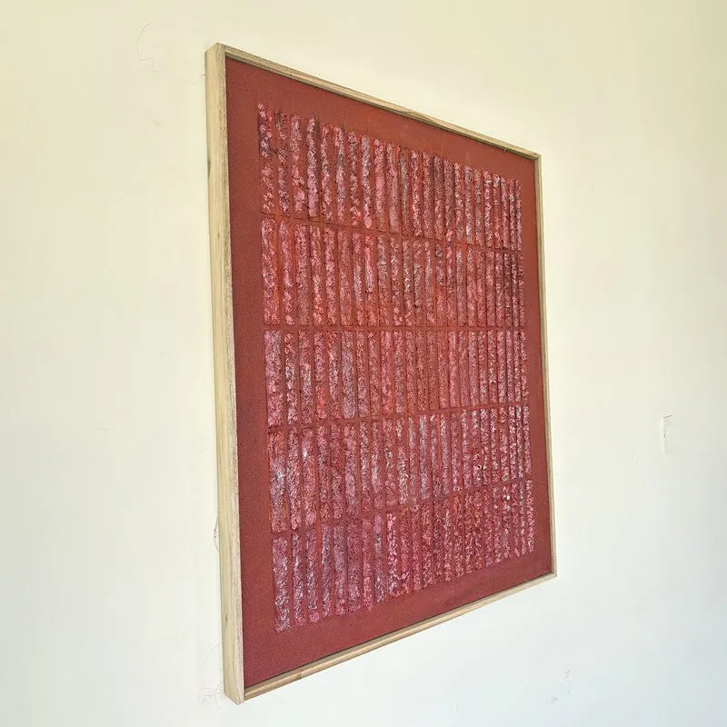Angled view of a framed maroon textured wall art piece