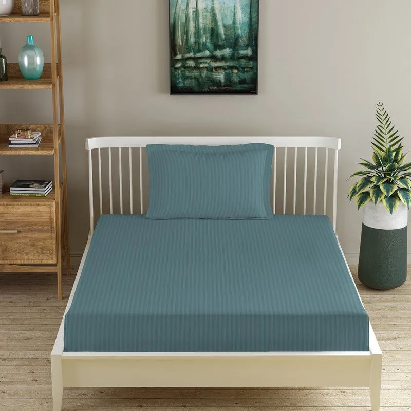 Teal striped fitted bedsheet on a bed with one matching pillow cover