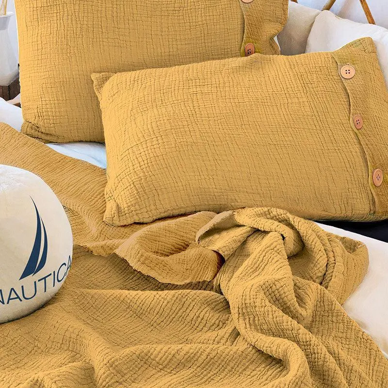 Close-up of yellow textured bedding and matching pillow cover with visible buttons