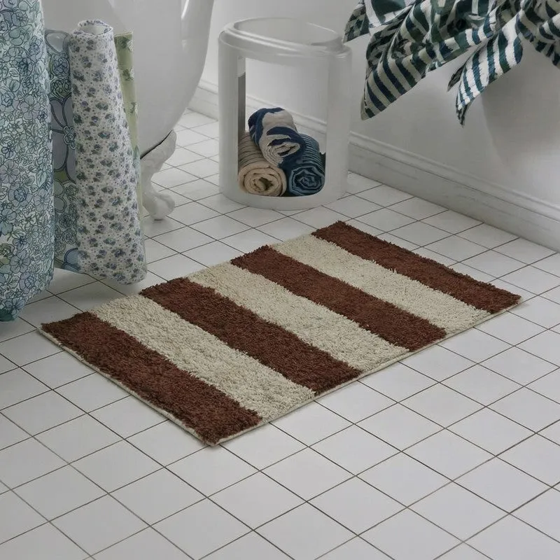Red and white striped bath mat near a bathtub and towel basket