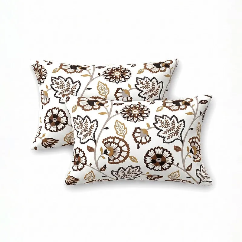 Two matching white and brown floral pillow covers on a plain background