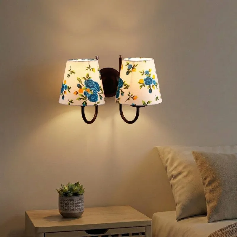 Blue and white twin wall lamp with floral cotton shades lit on a beige wall