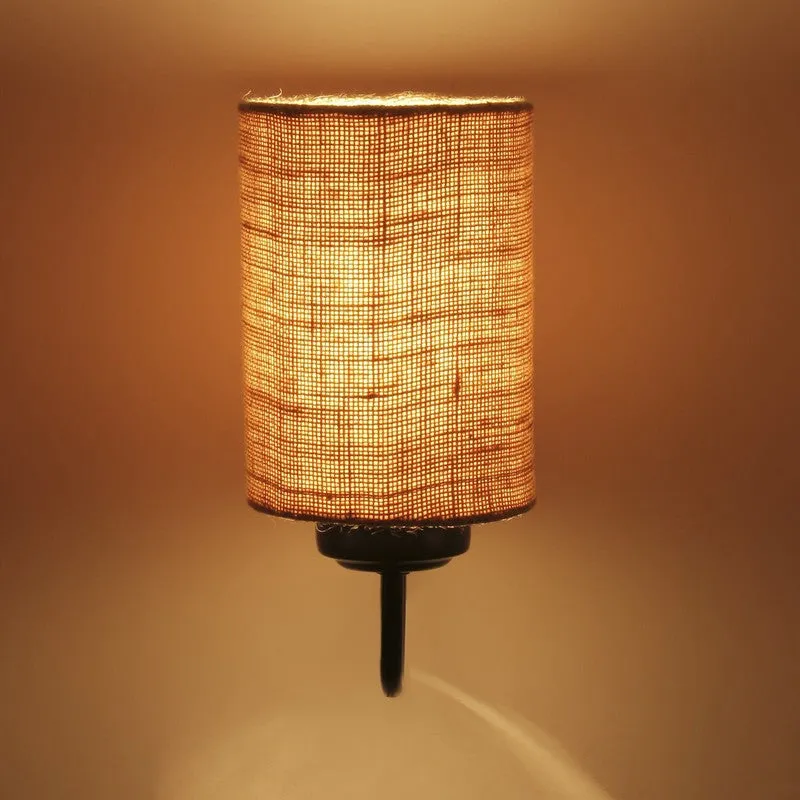 Close view of lit cylindrical jute wall lamp against a warm backdrop