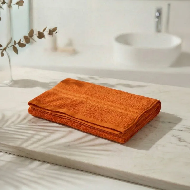 Folded orange bath towel displayed on a marble bathroom counter