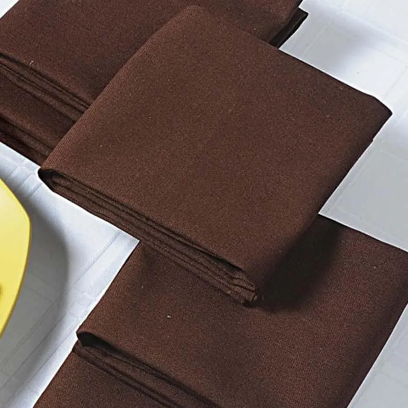 Folded brown table napkins stacked on a white tablecloth