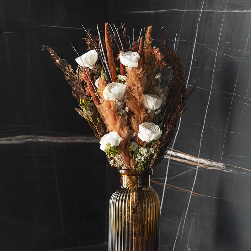 Close view of a dried bouquet with white flowers in an amber ribbed vase