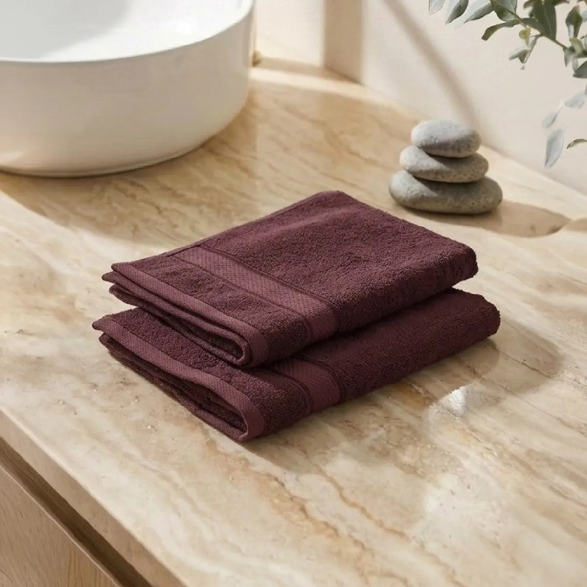 Two folded purple hand towels resting on a light stone surface