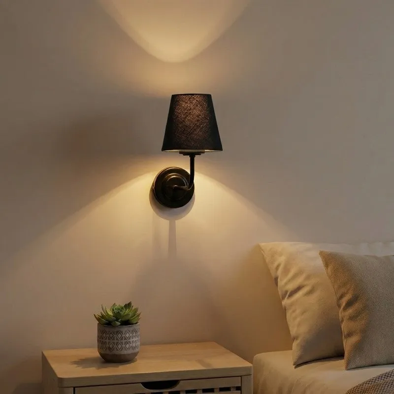 Black wall lamp with cotton shade mounted above a bedside table