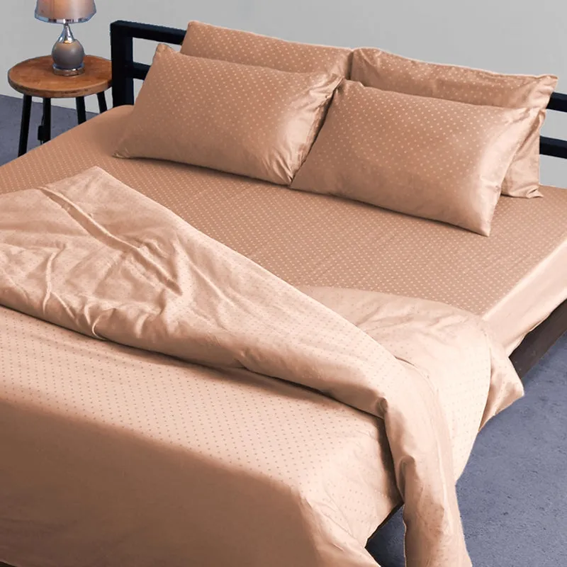 Peach dotted duvet cover draped across a bed with matching pillows