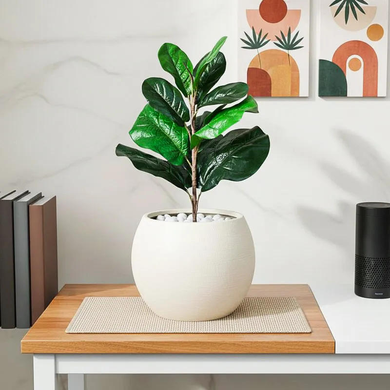 Green faux fiddle leaf fig plant displayed in a white planter on a wooden table