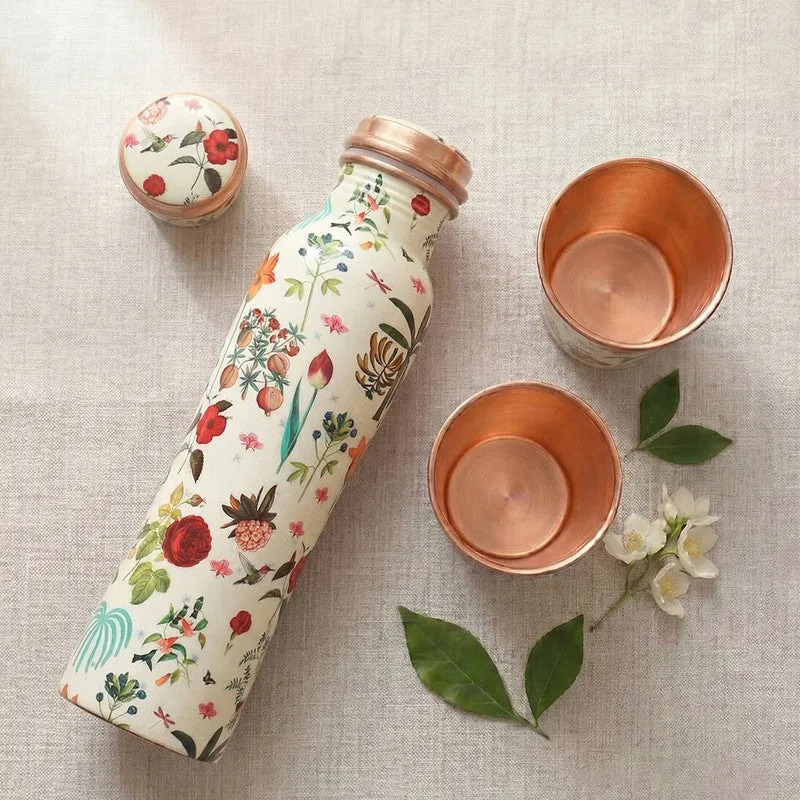Top view of a floral copper bottle and two tumblers on a neutral textile